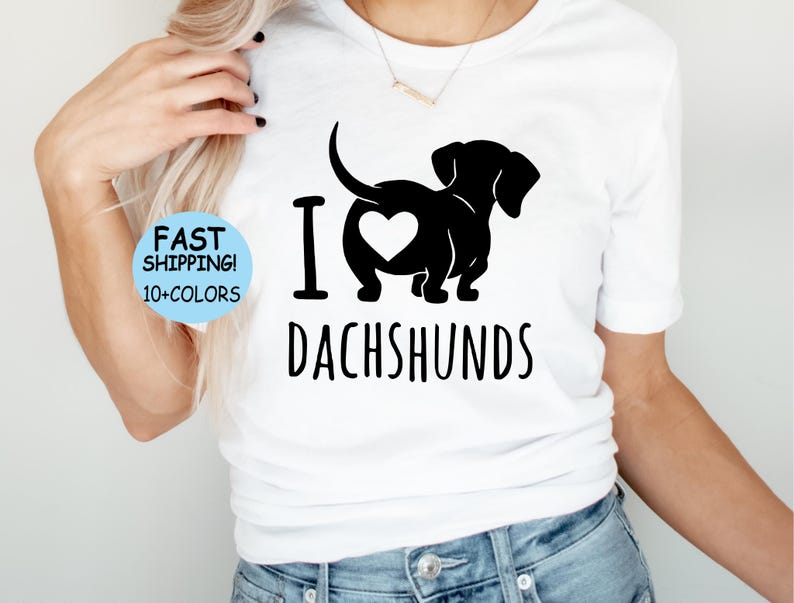 May include: White t-shirt with a black silhouette of a dachshund with a heart in its rear end. The text "I love dachshunds" is printed below the dog.
