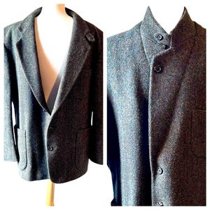 Puede incluir: Una chaqueta de tweed gris con un cierre de botón único y dos bolsillos de solapa. La chaqueta tiene un patrón de espiga y un cuello.