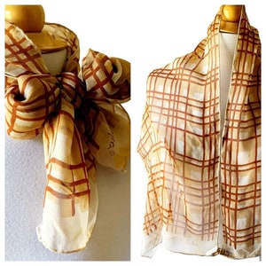 Peut inclure: Un foulard en soie beige à motif écossais brun et blanc. Le foulard porte l'inscription "Echo" en bas à droite et le mot "Echo" avec un symbole de copyright en bas à droite.