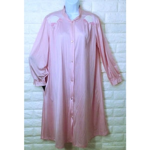 May include: A pink satin robe with long sleeves and a button-up front. The robe has white embroidered details on the shoulders.