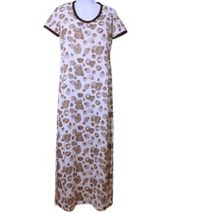 May include: A white, floor-length dress with a brown seashell pattern. The dress has short sleeves and a round neckline trimmed in brown. The overall design is a repeating pattern of various seashell shapes.