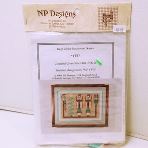 May include: A counted cross stitch kit titled "YEI" from NP Designs. The kit includes instructions and materials to create a 9 1/4" x 6 1/4" finished design of three figures in traditional Native American style.