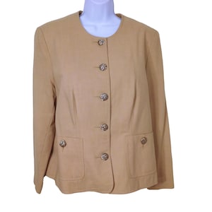 May include: A tan blazer with a round neckline and five gold buttons. The blazer has two pockets on the front and long sleeves.