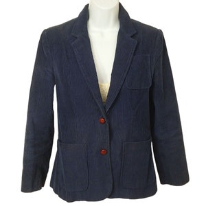 May include: A navy blue corduroy blazer with two button closures and two flap pockets. The blazer has a notched collar and long sleeves.
