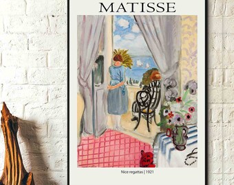 Könnte beinhalten: Ein gerahmter Druck eines Matisse-Gemäldes mit dem Titel "Nice regattas | 1921". Das Kunstwerk zeigt eine Frau, die aus einem Fenster auf eine Meereslandschaft blickt. Der Raum hat einen rosa gefliesten Boden, einen gestreiften Stuhl und eine Blumenvase.