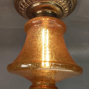 Peut inclure: Ancien luminaire de plafond avec une finition dorée. La lampe a un abat-jour en verre texturé en forme de cloche et une base en métal ornée. Le luminaire est suspendu à un support de plafond assorti. L'URL de la boutique Etsy est visible en bas.