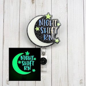 May include: A black and white glitter moon with the text "Night Shift RN" in colorful letters. The moon is attached to a clear badge holder with a black glitter button. The moon glows in the dark.