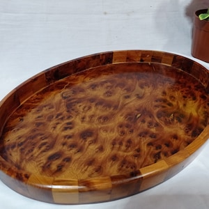 Peut inclure: Un grand plateau de service ovale en bois avec une finition en bois naturel. Le plateau présente un motif de grain de bois unique et est fait de plusieurs morceaux de bois.
