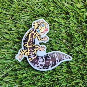 May include: A cartoon gecko sticker with a yellow, black, and purple pattern. The gecko is smiling with its tongue sticking out.