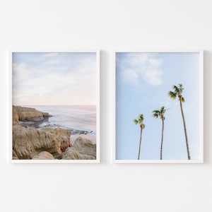 Puede incluir: Dos impresiones enmarcadas de escenas costeras. La primera impresión muestra un acantilado rocoso con vistas a un océano azul con un cielo nublado. La segunda impresión muestra tres palmeras contra un cielo azul con nubes blancas.