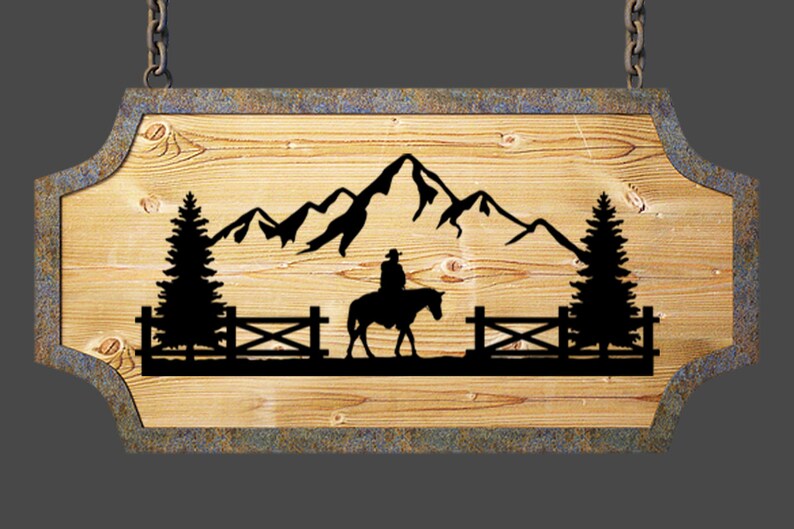 May include: A wooden sign with a rustic brown finish, featuring a silhouette of a cowboy riding a horse in front of a mountain range and two pine trees. The sign is hanging from two chains.
