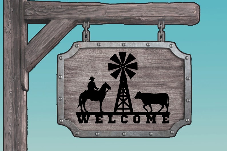 May include: A wooden sign with a metal frame and a rustic finish. The sign features a silhouette of a cowboy riding a horse, a windmill, and a cow. The sign says "WELCOME" in black lettering.