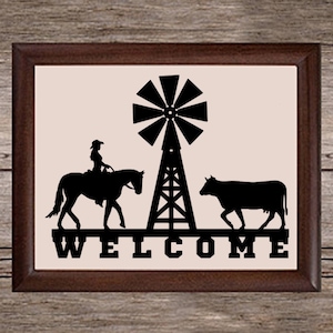 May include: A black and white silhouette of a cow, a horse with a rider, and a windmill with the word "WELCOME" underneath. The image is framed in a brown wood frame.