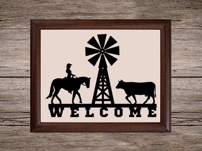 May include: A black and white silhouette of a cow, a horse with a rider, and a windmill with the word "WELCOME" underneath. The image is framed in a brown wood frame.