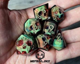 May include: Set of seven green, brown, and gold dice with skull and floral patterns. The dice are numbered 1 through 6.