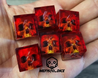 May include: Six red and orange dice with a skull design and the number six on each face. The dice are on a hand.