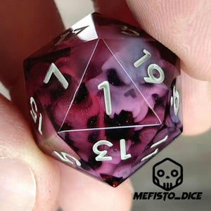 May include: A purple and white d20 dice with a skull design. The dice is made of clear resin with a swirling pattern of purple and white.