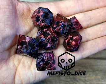 May include: Set of seven purple and red dice with a skull design. The dice are made of resin and have a marbled effect. The dice are in a hand, and the background is a wooden surface. The text "MEFISTO_DICE" is visible in the bottom right corner of the image.