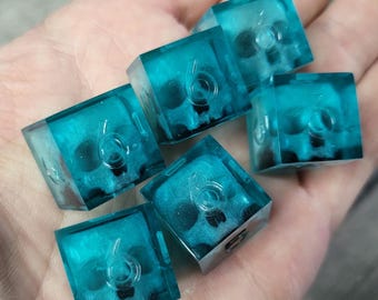 May include: Six teal blue dice with a skull design and the number six on each face.