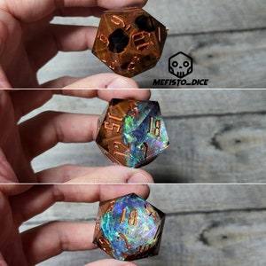 Può includere: Un dado iridiscente multi-sfaccettato con numeri color rame. Il dado è un d6, con i numeri 1, 2, 3, 4, 5 e 6 visibili. Il dado è fatto di un materiale trasparente con un effetto scintillante e iridescente.