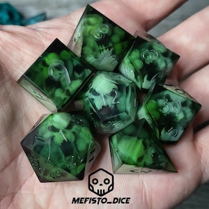 Puede incluir: Conjunto de siete dados verdes con un diseño de calavera y huesos cruzados. Los dados son translúcidos y muestran una calavera y huesos cruzados blancos en el interior. Los dados están numerados del 1 al 6.