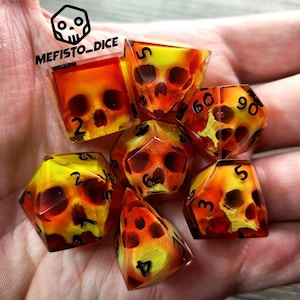Può includere: Un set di sette dadi con un design a forma di teschio. I dadi sono realizzati in resina trasparente con uno schema di colori rosso e giallo. I dadi sono numerati da 1 a 6. I dadi sono etichettati "Mefisto Dice".