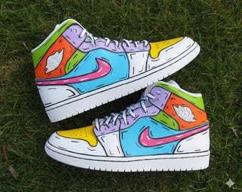 May include: A pair of colorful high-top sneakers with a white base. The shoes feature panels of yellow, green, orange, purple, and blue, outlined in black. A pink swoosh is on the side, and the iconic Jordan logo is visible.