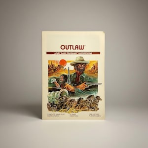 May include: A vintage Atari Outlaw game cartridge box. The cover art features a Western-themed illustration with cowboys, a stagecoach, and a sunset. The title "OUTLAW" is displayed in bold, red letters above the artwork. The box includes game instructions and variations.