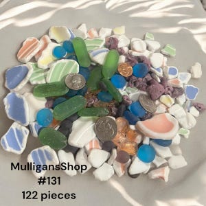 May include: A collection of 122 pieces of sea glass and other beach finds, including white, blue, green, and pink glass, as well as shells and stones. The collection is labeled "MulligansShop #131".