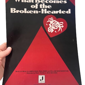 May include: Sheet music cover for "What Becomes of the Broken-Hearted" with a black background and red accents. The title is in white, with a red heart and floral design. The cover also includes the names of the songwriters and the recording artist.