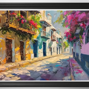 May include: Oil painting of a sunlit street scene with colorful buildings and vibrant flowers. The artwork depicts a European town with white and pastel-colored buildings, balconies, and cobblestone streets. The painting is framed in a black frame.
