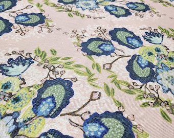 May include: A light pink fabric featuring a repeating floral pattern in shades of navy blue, light blue, and lime green. The design consists of stylized blossoms and leaves arranged in a symmetrical layout across the textured textile surface.