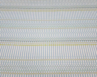 May include: A woven fabric featuring a repeating geometric pattern of vertical light blue and white stripes, interspersed with horizontal bands of small, alternating squares in shades of yellow, light green, and grey against a white background.