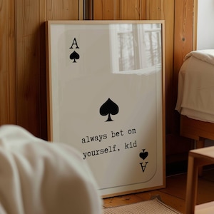 Puede incluir: Una impresi&oacute;n enmarcada de una carta de juego de as de picas con el texto "always bet on yourself, kid" impreso debajo de la carta.