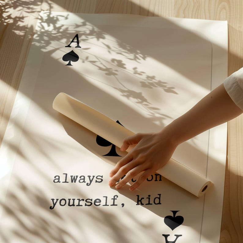 Puede incluir: Un p&oacute;ster blanco con texto negro y un dise&ntilde;o de carta de juego de picas negra. El texto dice "always bet on yourself, kid". Una mano est&aacute; enrollando el p&oacute;ster.