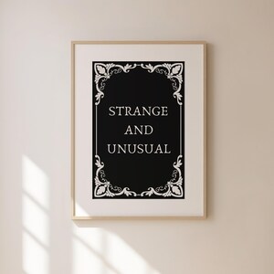 May include: A black and white printable wall art print with a decorative frame and the text "Strange and Unusual".
