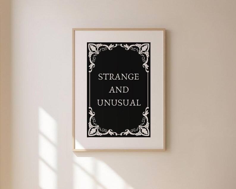 May include: A black and white printable wall art print with a decorative frame and the text "Strange and Unusual".