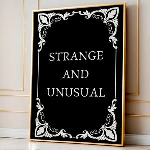 May include: Black and white framed print with a decorative border and the text "STRANGE AND UNUSUAL".