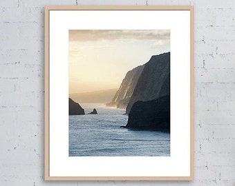 May include: A photograph of a dramatic seascape with steep cliffs and a calm ocean. The sky is a soft blue with hints of pink and orange from the setting sun.