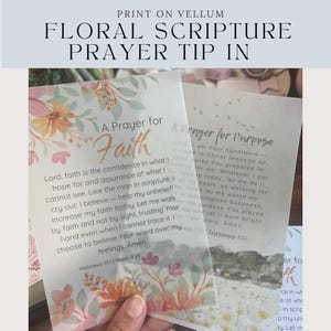 Op de afbeelding: Twee doorschijnende vellum vellen met bloemenillustraties en gedrukte tekst. Het voorste vel toont A Prayer for Faith met oranje en roze bloemen. Het vel erachter toont A Prayer for Purpose met een landschapsafbeelding.