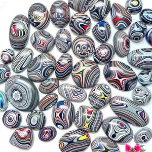 May include: A selection of polished stones featuring intricate swirling patterns in grey, black, red, yellow, and blue. The stones are of various sizes and shapes, including oval and rounded forms. The image showcases natural artistry.