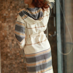 Peut inclure: Une robe blanche &agrave; capuche avec des rayures brunes et grises. La robe a une ceinture &agrave; nouer et est faite d'un mat&eacute;riau doux et absorbant.