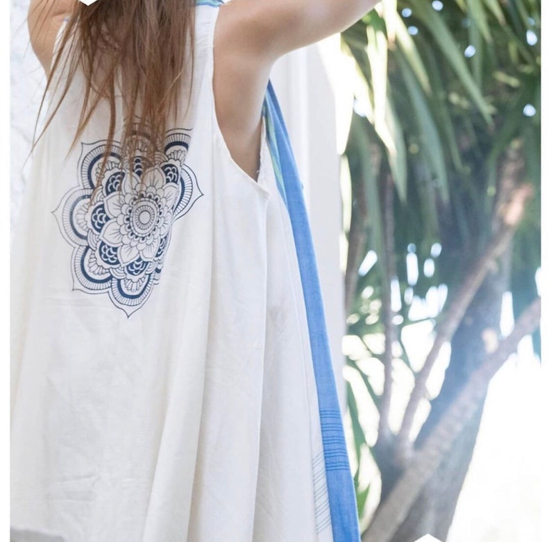 May include: White sleeveless top with a blue mandala design on the back. The top is made of a lightweight fabric and has a flowy silhouette.
