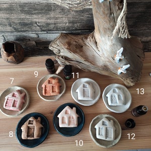 Könnte beinhalten: Ein Set aus zehn keramischen Häusern in Form von Diffusoren mit verschiedenen Farben und Designs. Jeder Diffusor sitzt auf einer kleinen Keramikschale. Die Diffusoren sind von 7 bis 13 nummeriert.