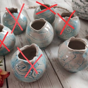 Könnte beinhalten: Sechs kleine, runde, weiße Keramik-Blumentöpfe mit blau-weißem Craquelé-Glanz. Die Töpfe haben eine raue, strukturierte Oberfläche und eignen sich perfekt für die Präsentation kleiner Pflanzen oder Sukkulenten.