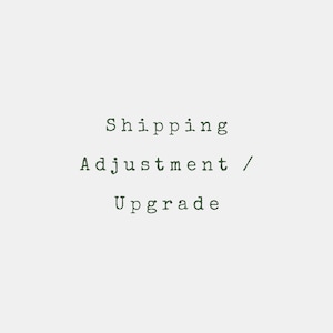 May include: Text on a light gray background reads "Shipping Adjustment / Upgrade" in a dark green typewriter font. The text is centered and stacked vertically.