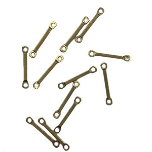 May include: A group of 12 gold-colored metal connector pieces. Each piece has two small loops on either end.