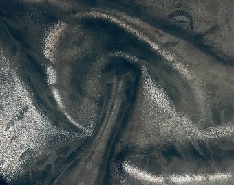 May include: Close-up of a silver fabric with a subtle shimmer. The fabric is wrinkled and has a soft, luxurious feel.