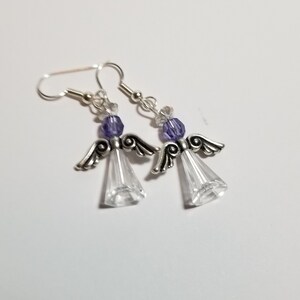 May include: A pair of silver angel-shaped earrings with clear crystal accents and purple beads.