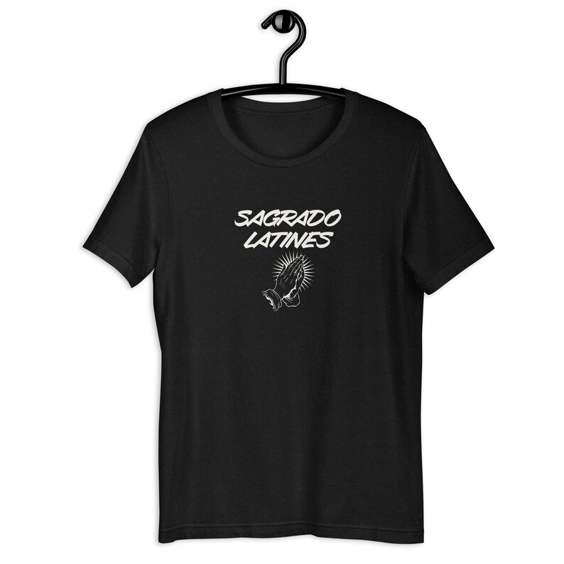 May include: Black t-shirt with white text that reads "Sagrado Latines" and a white image of praying hands.